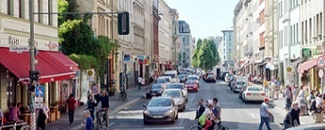 Straßen mit Altbauten und Autos, links eine rote Markise